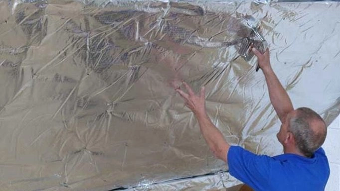 A man using a staple gun on insulation