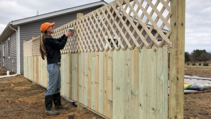 A woman using a staple gun on a lattice