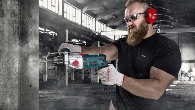 A construction worker using Ronix best corded hammer drill for heavy-duty drilling in concrete