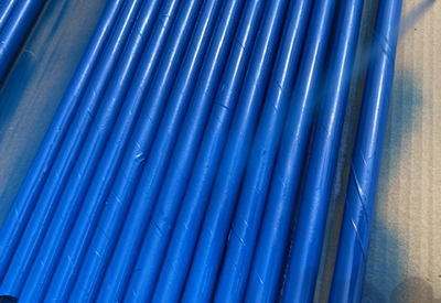 Blue spray paint is used to coat the taped PVC pipe.